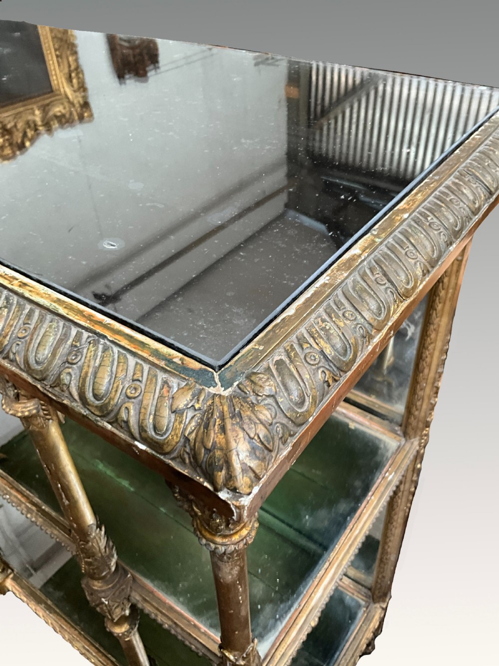 An ornate Victorian giltwood display shelf featuring three glass-tiered levels, a mirrored back panel, and intricate carved gesso columns with decorative moulding. View IV