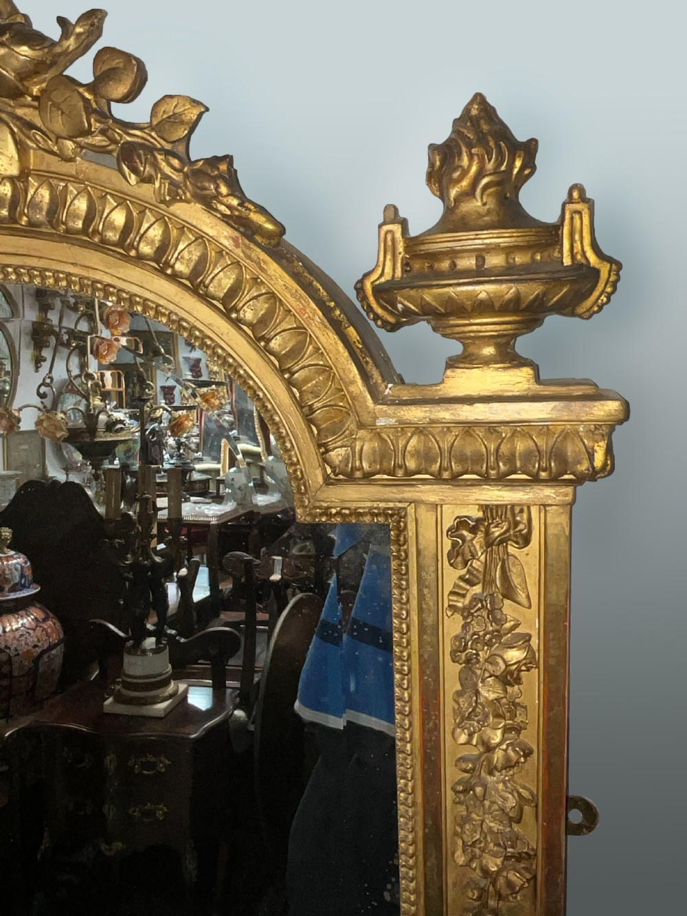 A large 19th-century French arched giltwood wall mirror with detailed wreath cresting and corner finials. View III