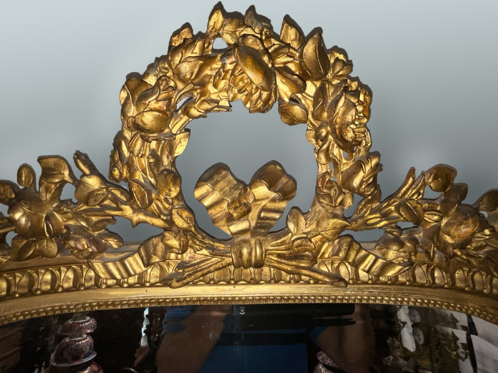 A large 19th-century French arched giltwood wall mirror with detailed wreath cresting and corner finials. View IV