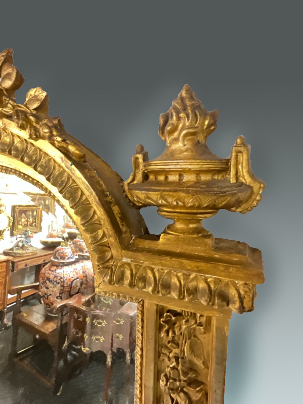 A large 19th-century French arched giltwood wall mirror with detailed wreath cresting and corner finials. View V