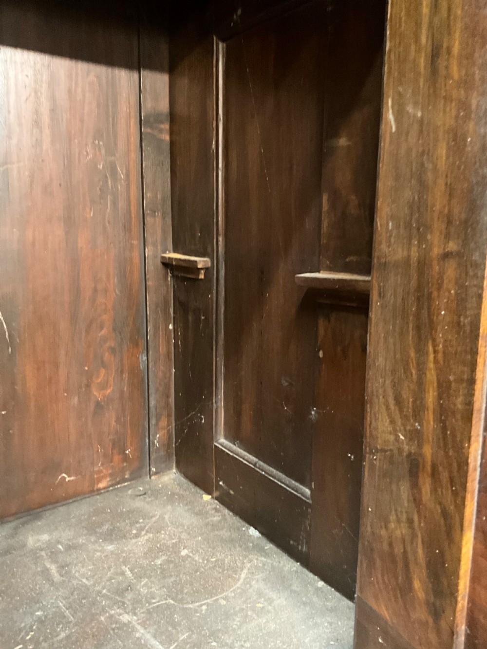 A tall dark walnut cabinet featuring detailed classical relief carvings on two door panels flanked by turned columns. View V