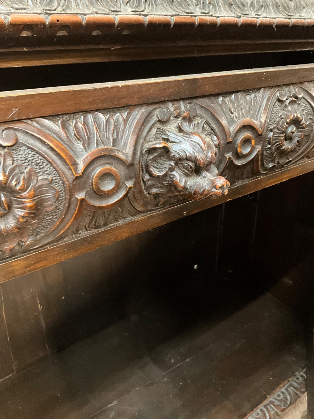 A tall dark walnut cabinet featuring detailed classical relief carvings on two door panels flanked by turned columns. View VIII