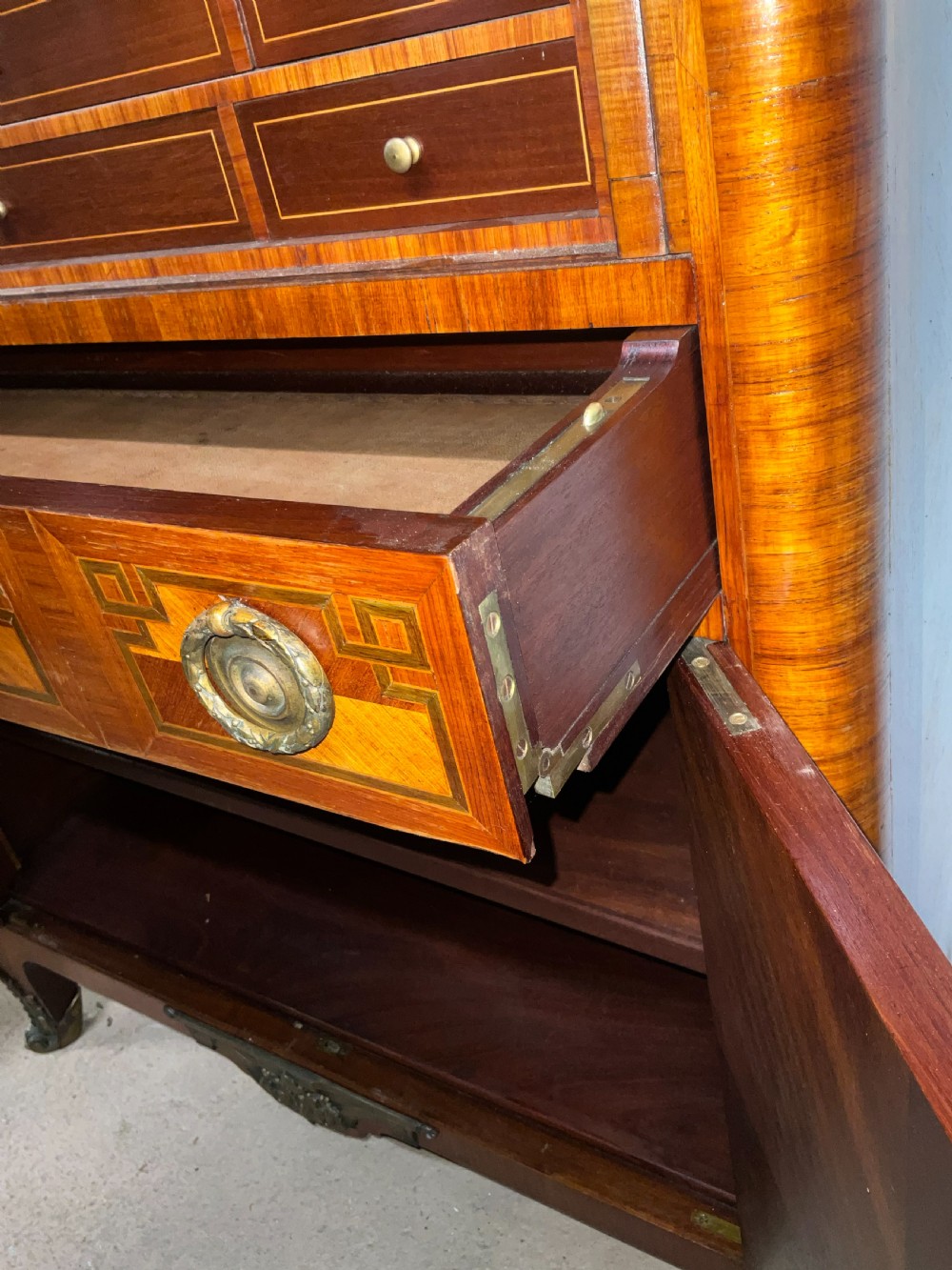 An antique French style marquetry writing cabinet featuring a marble top, tambour shutter front, middle drawer, floral inlaid doors, and brass mounts. View II