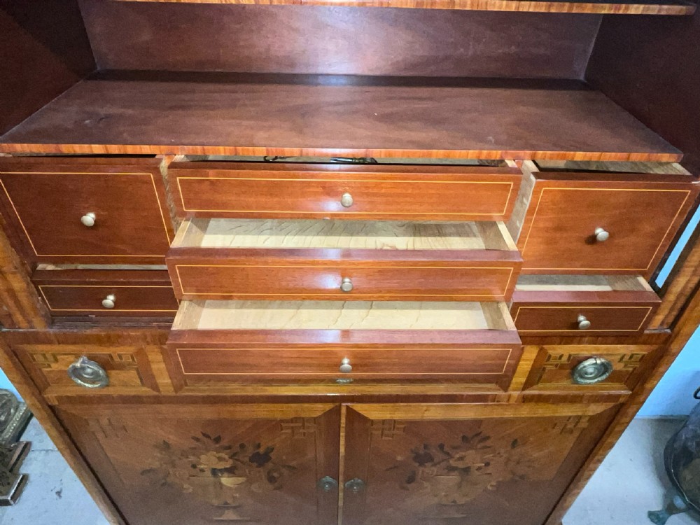 An antique French style marquetry writing cabinet featuring a marble top, tambour shutter front, middle drawer, floral inlaid doors, and brass mounts. View V