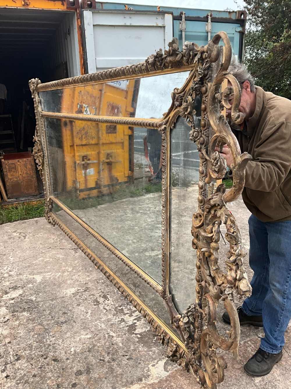 A large nineteenth-century French giltwood border mirror featuring a elaborate rococo crested top, egg and dart moulding, and marginal glass panels. View III