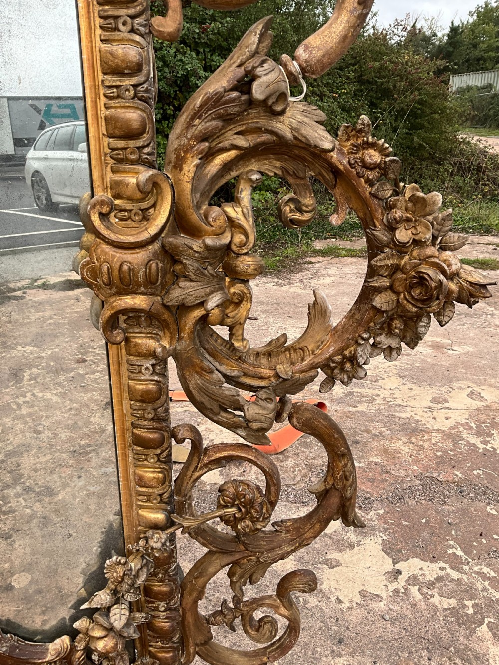 A large nineteenth-century French giltwood border mirror featuring a elaborate rococo crested top, egg and dart moulding, and marginal glass panels. View IV