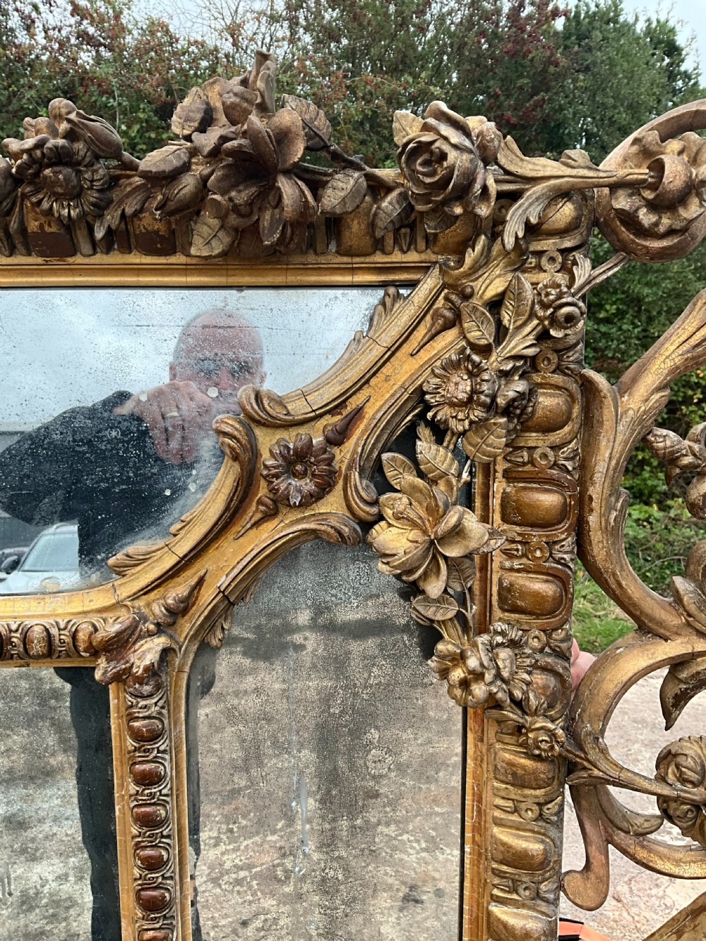 A large nineteenth-century French giltwood border mirror featuring a elaborate rococo crested top, egg and dart moulding, and marginal glass panels. View VI