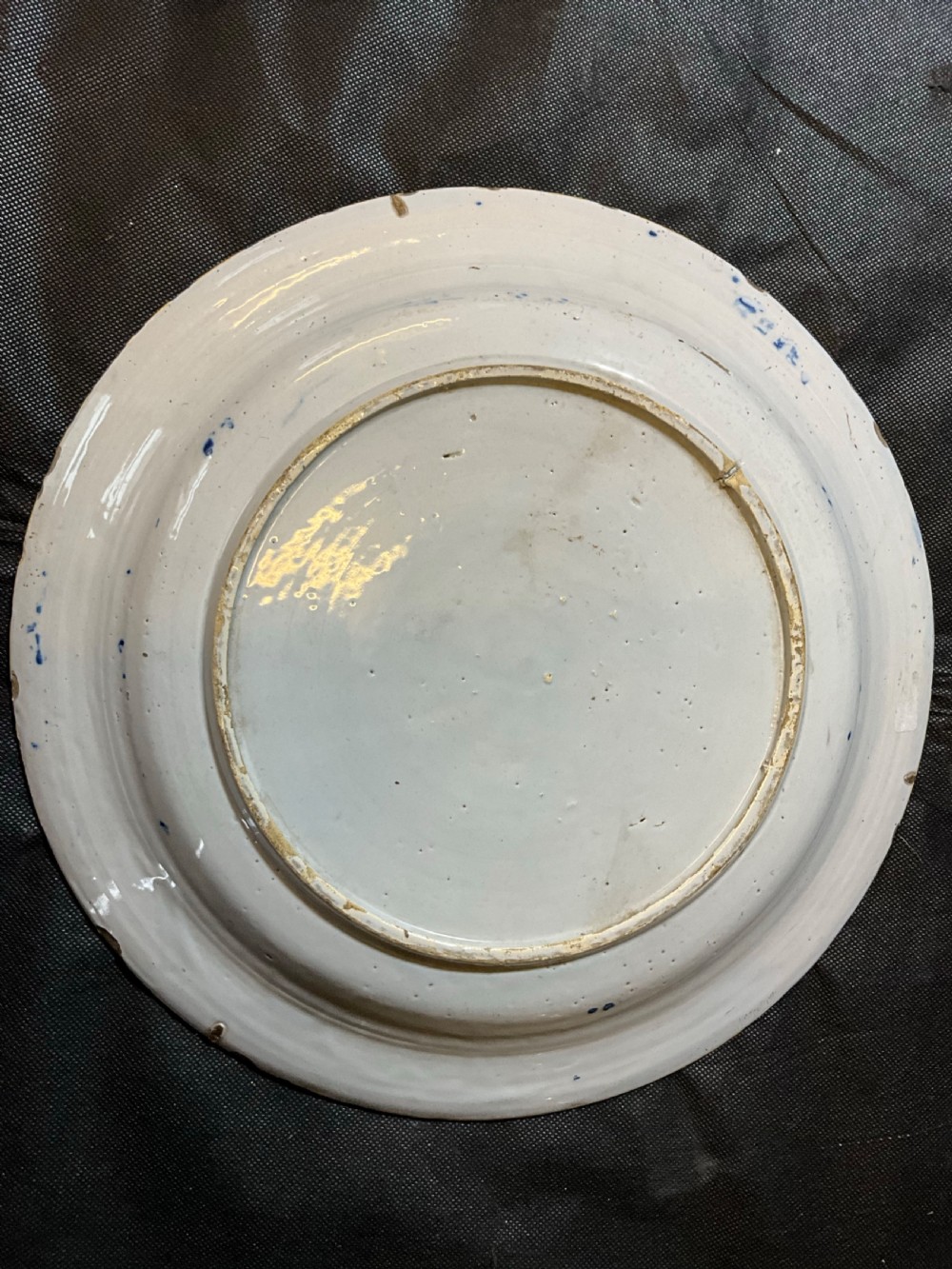 An antique circular tin-glazed earthenware plate featuring hand-painted cobalt blue floral motifs on a white background with a yellow rim. View VIII