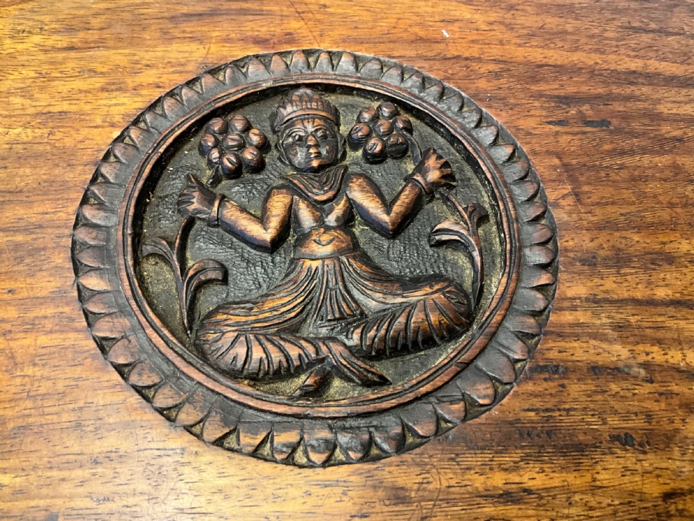 A 19th-century octagonal Burmese dark wood occasional table featuring detailed floral relief carvings, frieze drop finials, and a pedestal base carved as a mythical creature. View II