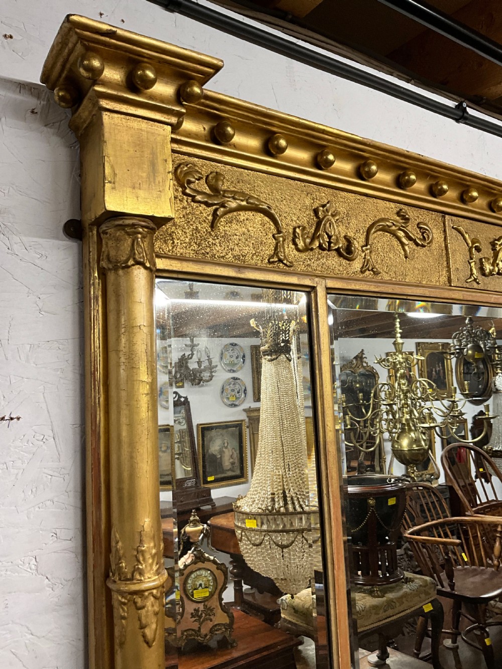 An early 19th-century Regency gilded overmantel mirror featuring a triple-plate mirror design, fluted columns, and ball moulding details. View III