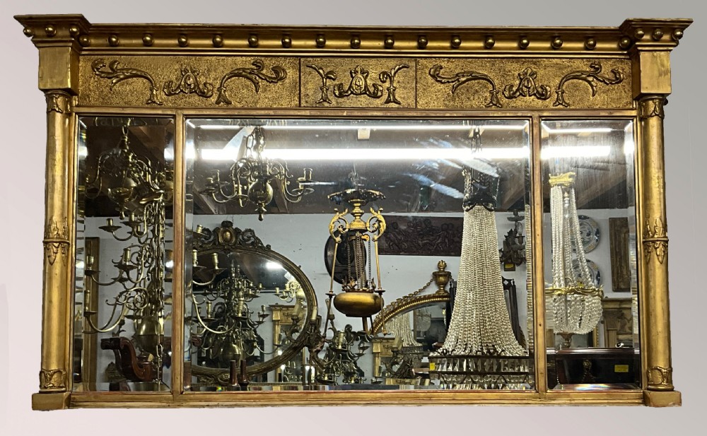 An early 19th-century Regency gilded overmantel mirror featuring a triple-plate mirror design, fluted columns, and ball moulding details. View VII