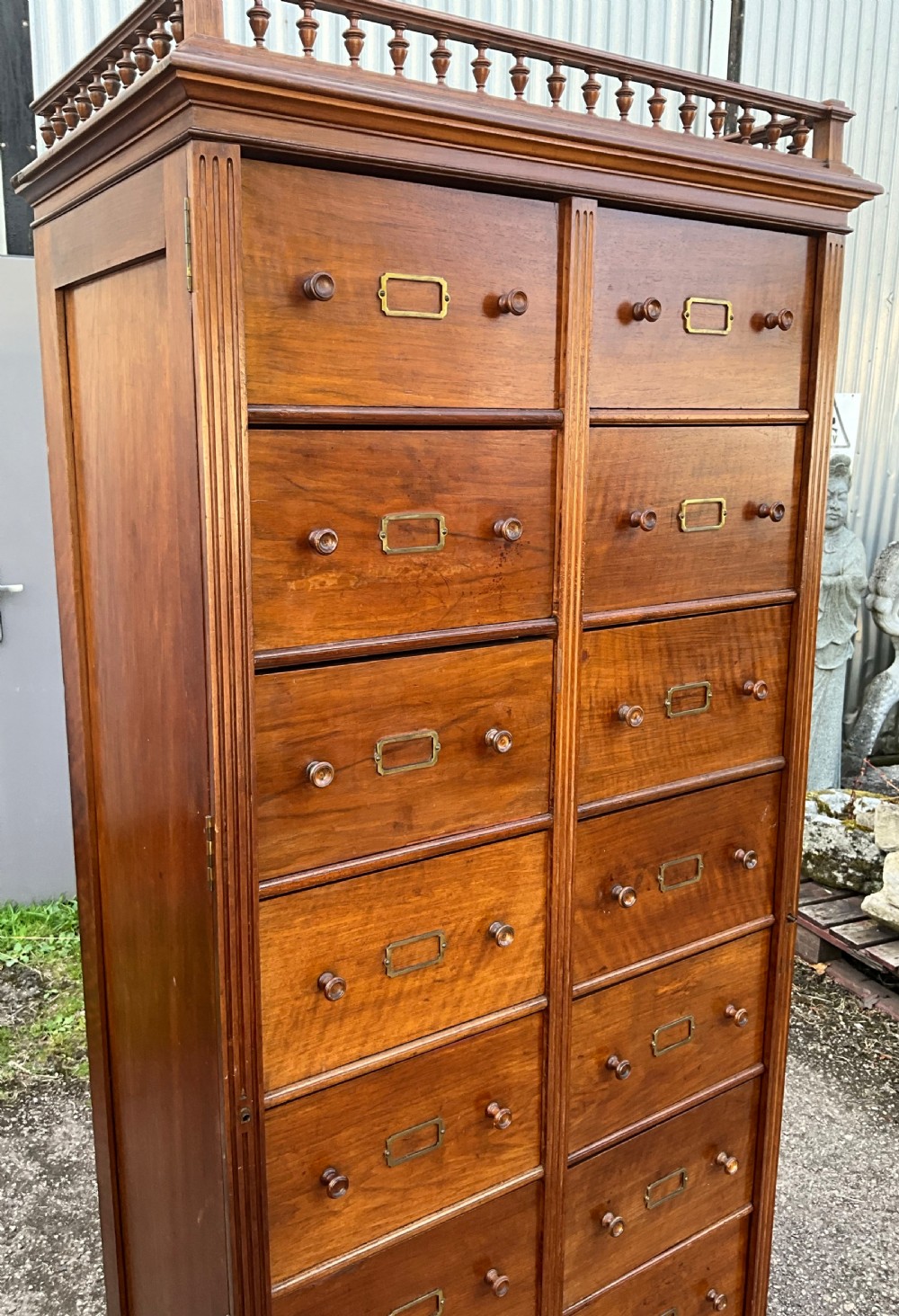 A tall 19th-century walnut bank of sixteen drawers featuring central brass label holders, turned wooden knobs, and a spindle gallery top rail. View III