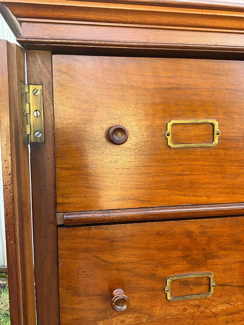 A tall 19th-century walnut bank of sixteen drawers featuring central brass label holders, turned wooden knobs, and a spindle gallery top rail. View V