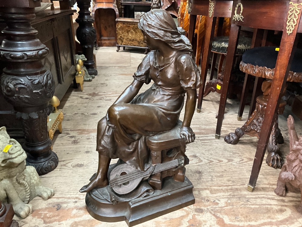 A dark patinated bronze statue depicting a seated young woman resting her foot on a rock next to a lute, with Mignon inscribed on the base. View V