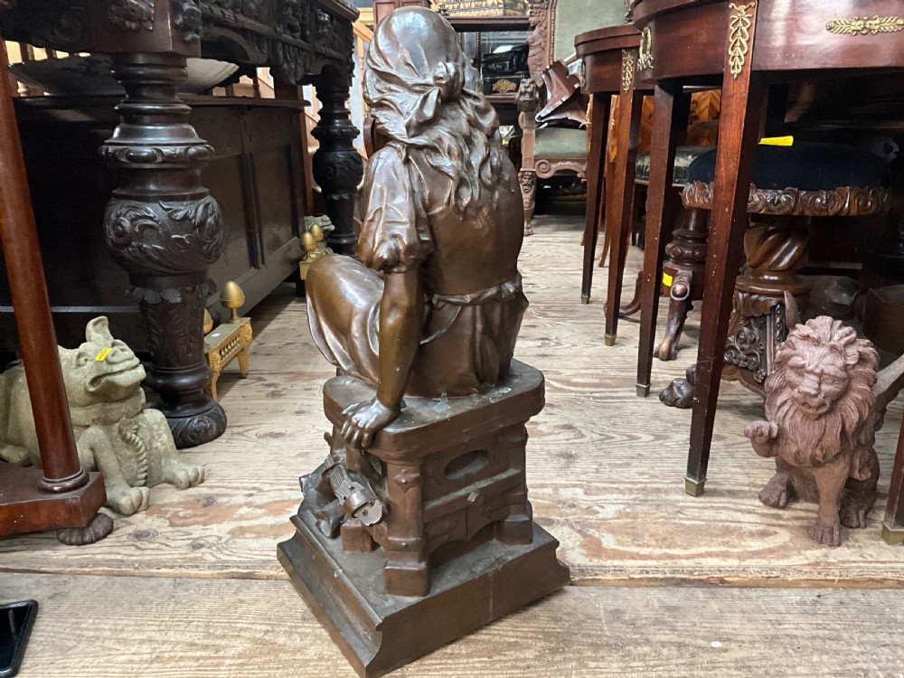 A dark patinated bronze statue depicting a seated young woman resting her foot on a rock next to a lute, with Mignon inscribed on the base. View VII