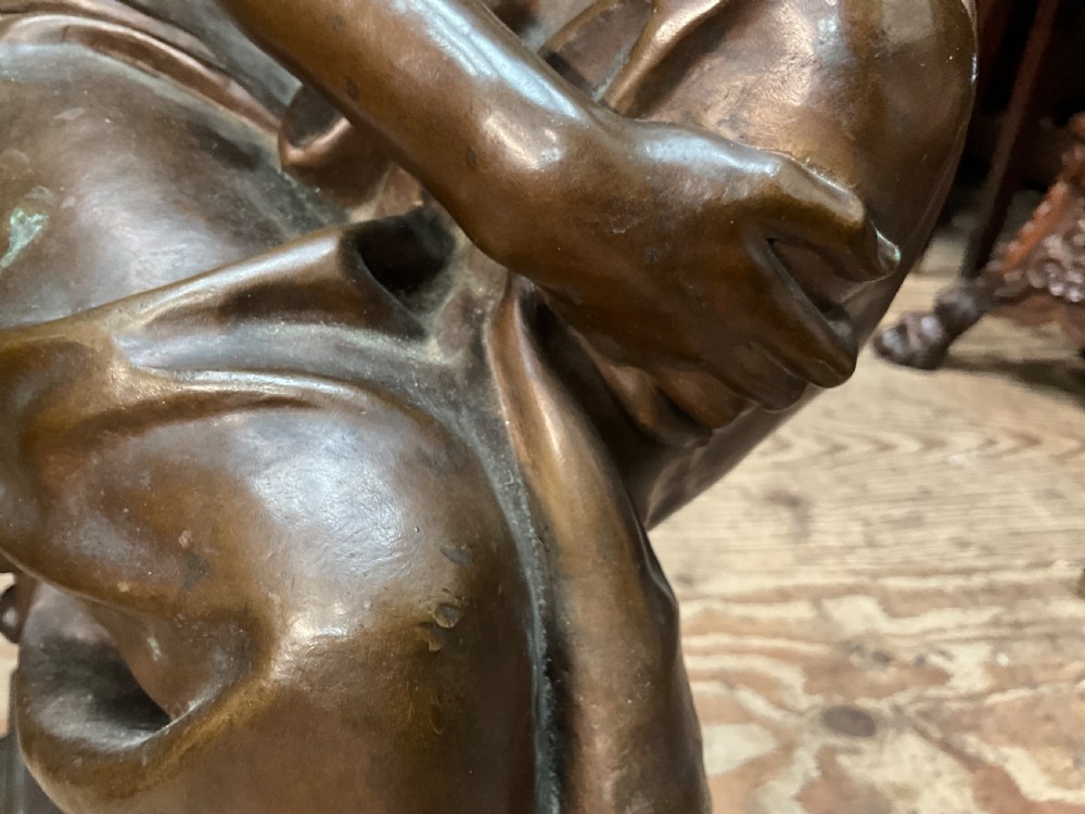 A dark patinated bronze statue depicting a seated young woman resting her foot on a rock next to a lute, with Mignon inscribed on the base. View X