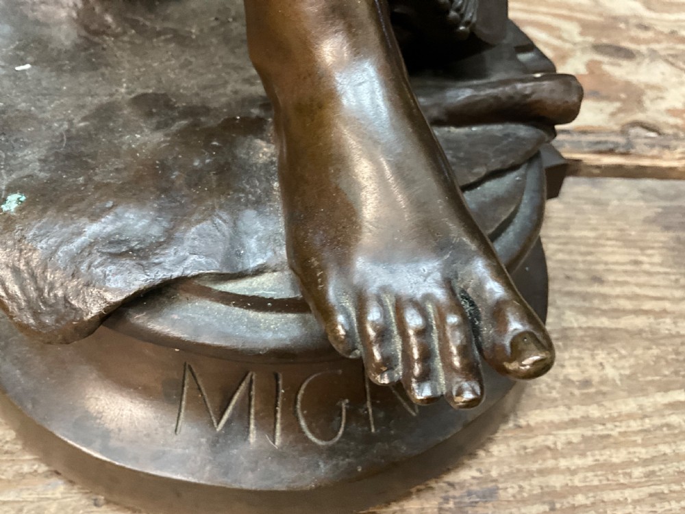 A dark patinated bronze statue depicting a seated young woman resting her foot on a rock next to a lute, with Mignon inscribed on the base. View XI