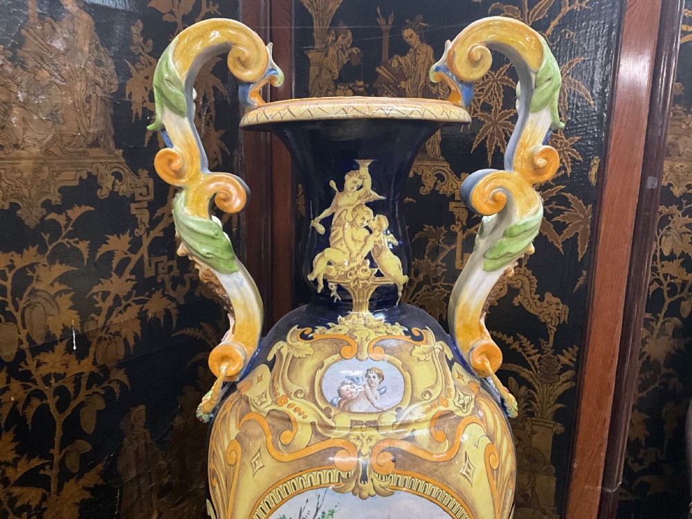 Large Italian Majolica tin-glazed earthenware vase with scrolled handles resting on an ornate matching pedestal base, decorated with painted mythological figures and relief masks. View VIII