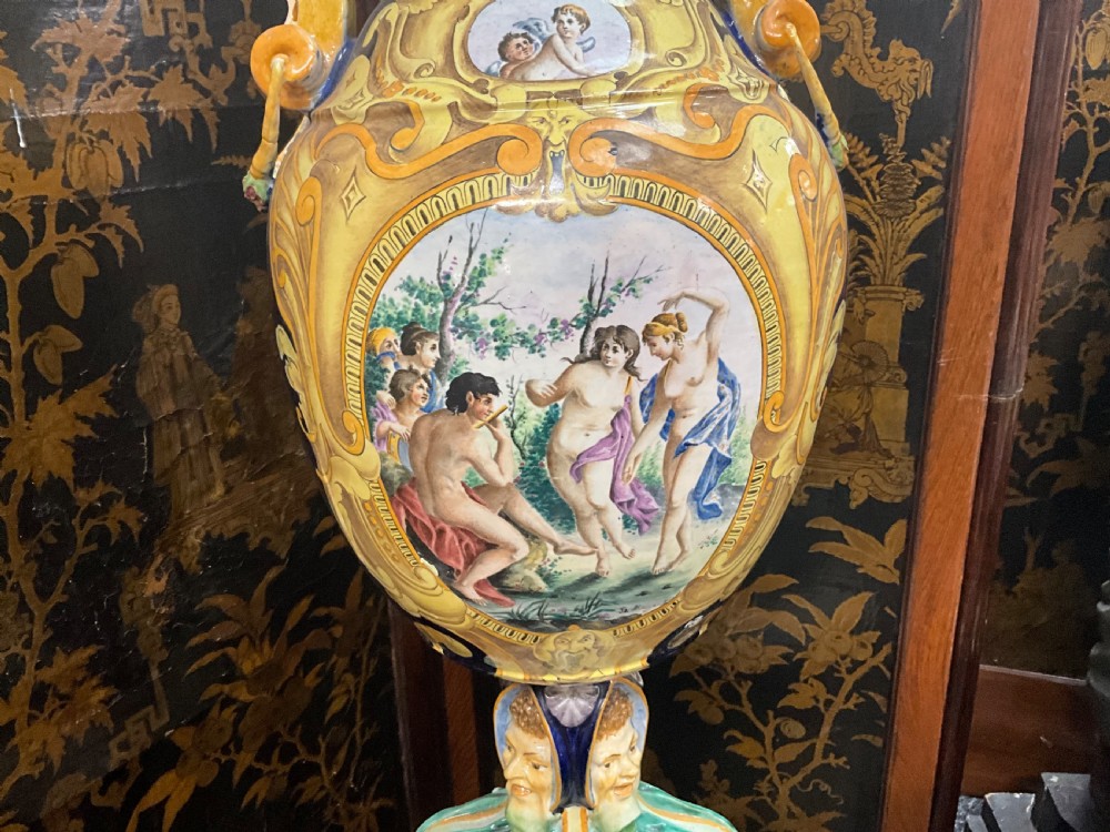 Large Italian Majolica tin-glazed earthenware vase with scrolled handles resting on an ornate matching pedestal base, decorated with painted mythological figures and relief masks. View IX