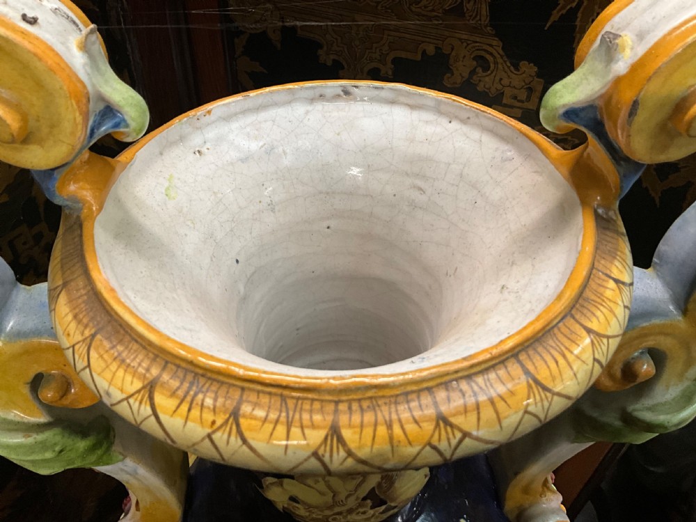 Large Italian Majolica tin-glazed earthenware vase with scrolled handles resting on an ornate matching pedestal base, decorated with painted mythological figures and relief masks. View XIV
