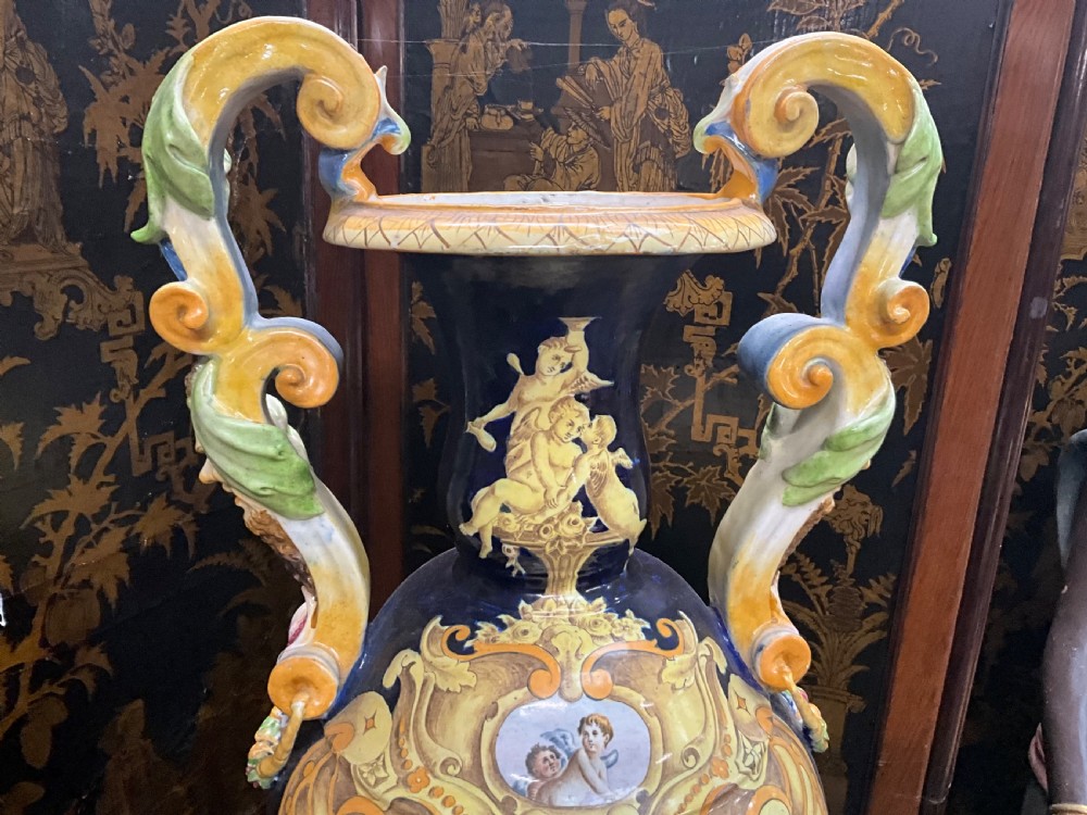 Large Italian Majolica tin-glazed earthenware vase with scrolled handles resting on an ornate matching pedestal base, decorated with painted mythological figures and relief masks. View XV