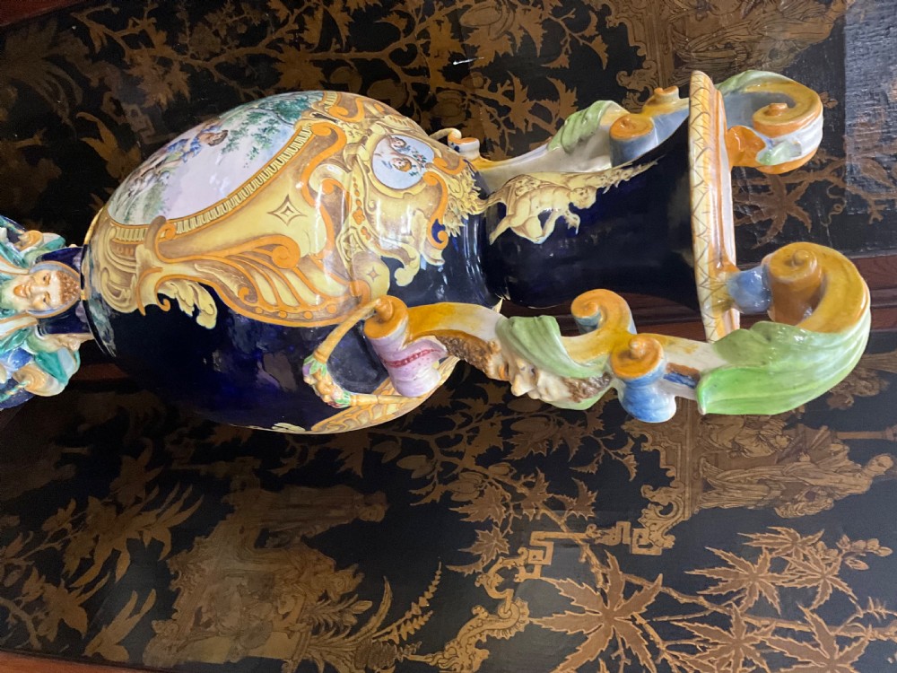 Large Italian Majolica tin-glazed earthenware vase with scrolled handles resting on an ornate matching pedestal base, decorated with painted mythological figures and relief masks. View XVII