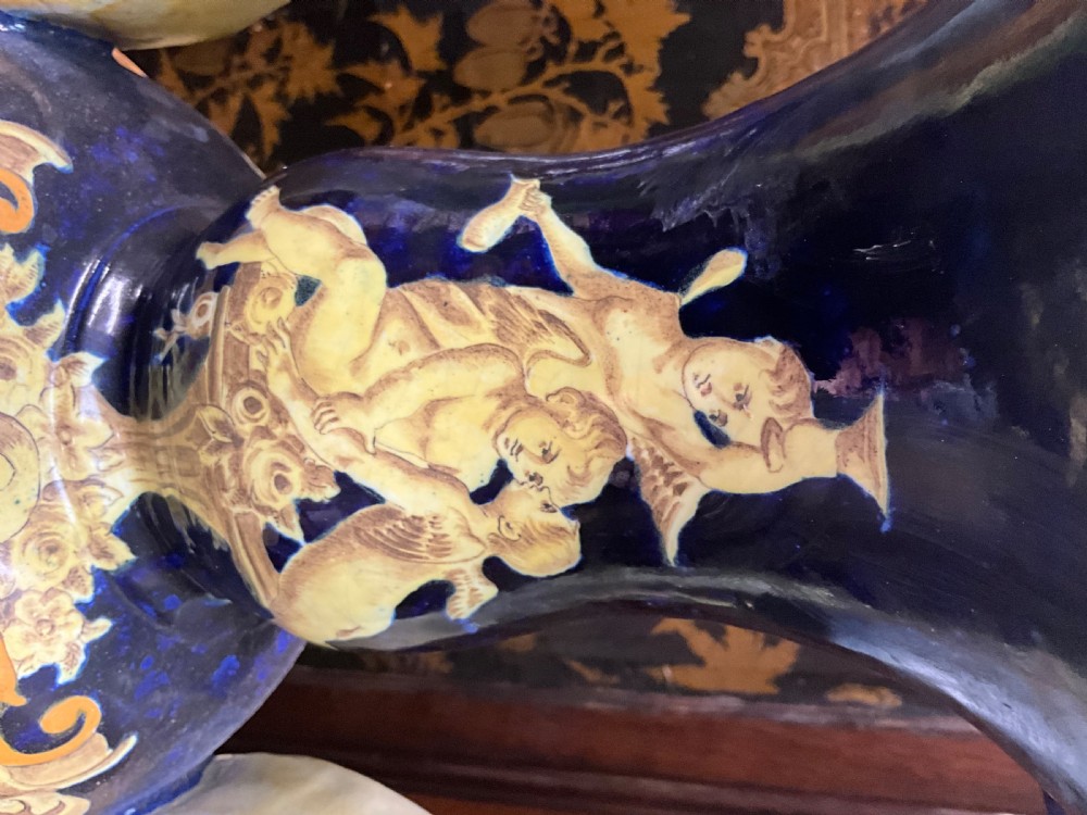 Large Italian Majolica tin-glazed earthenware vase with scrolled handles resting on an ornate matching pedestal base, decorated with painted mythological figures and relief masks. View XXI