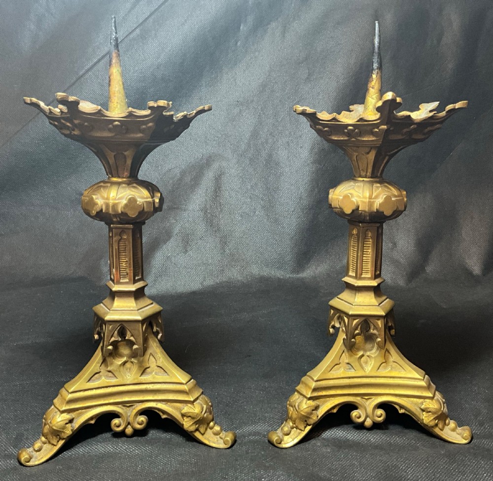 A pair of brass Gothic style candlesticks.