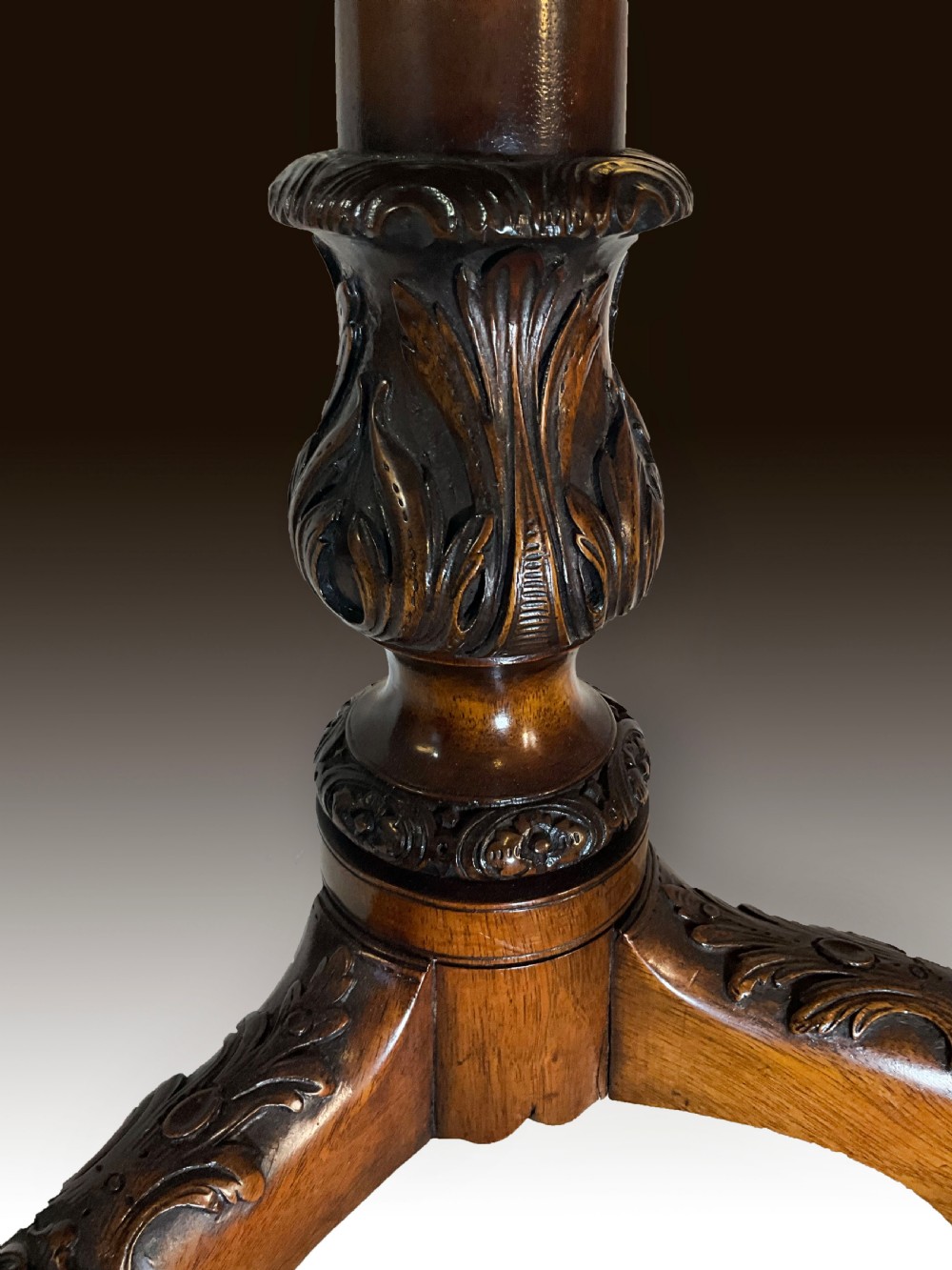A mahogany tilt-top table positioned vertically to show a carved scalloped rim and a tripod base with cabriole legs. View III