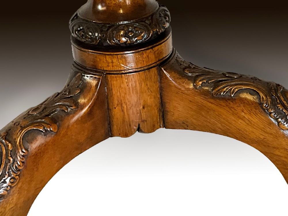 A mahogany tilt-top table positioned vertically to show a carved scalloped rim and a tripod base with cabriole legs. View IV