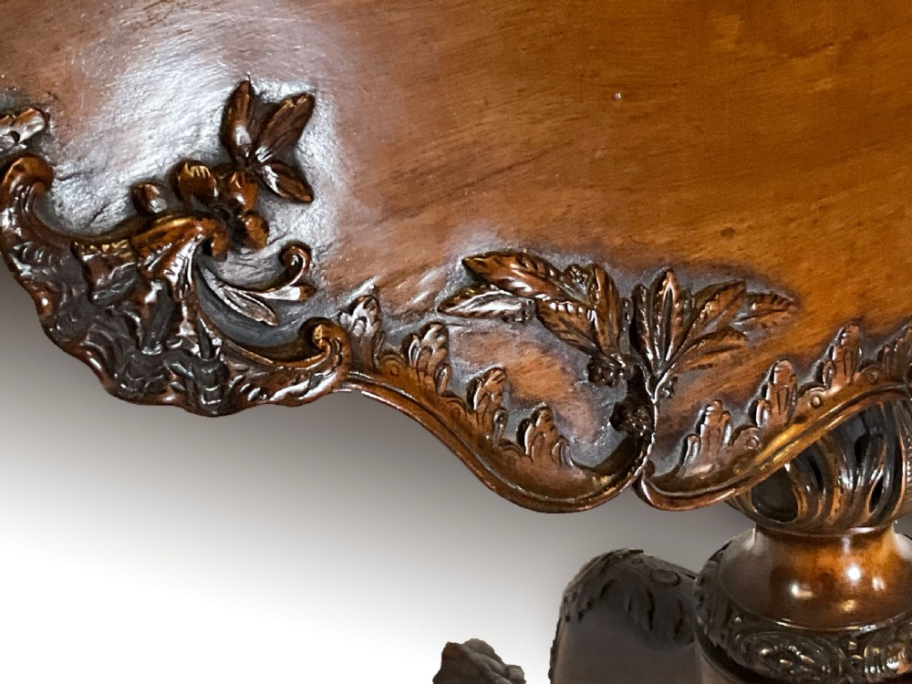 A mahogany tilt-top table positioned vertically to show a carved scalloped rim and a tripod base with cabriole legs. View V