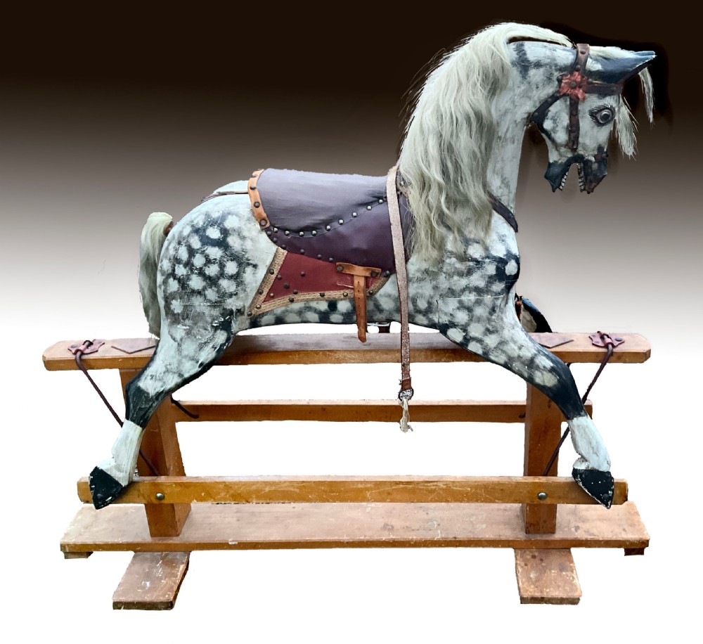 An antique carved wooden dapple grey rocking horse with real horsehair and leather tack mounted on a pine safety glider stand.