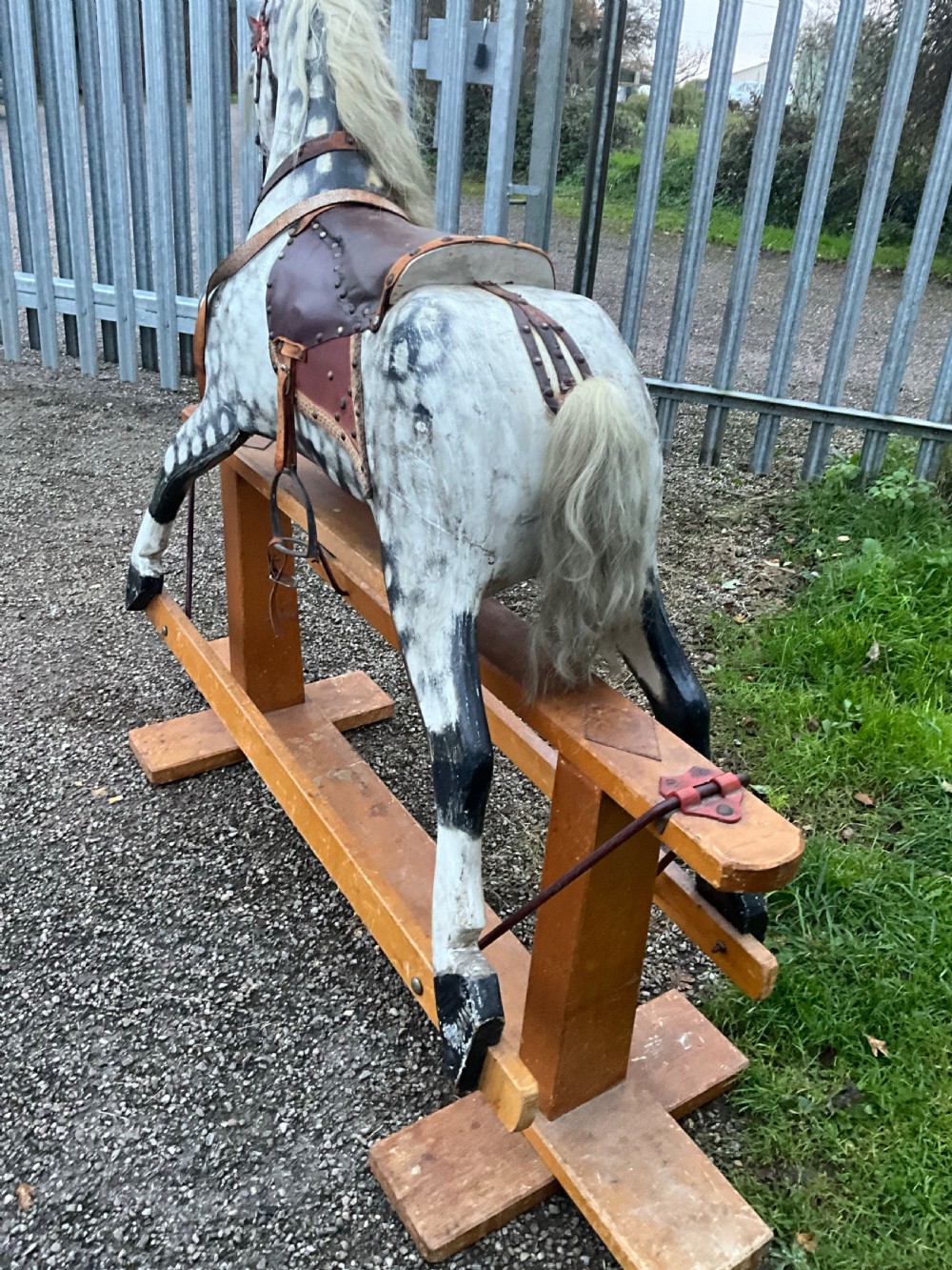 An antique carved wooden dapple grey rocking horse with real horsehair and leather tack mounted on a pine safety glider stand. View II