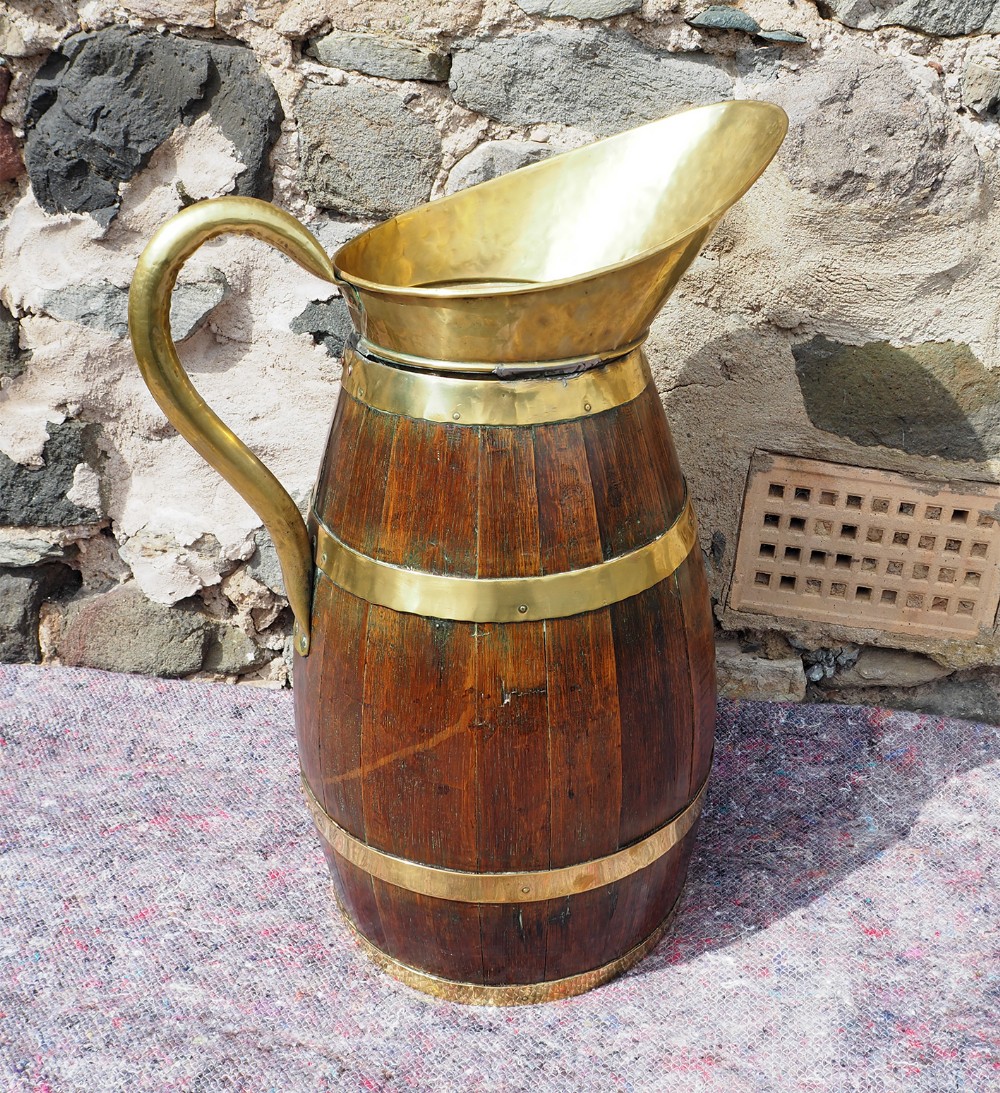 A large Victorian coopered oak jug featuring polished brass binding bands, an elongated brass spout, and a curved brass handle.