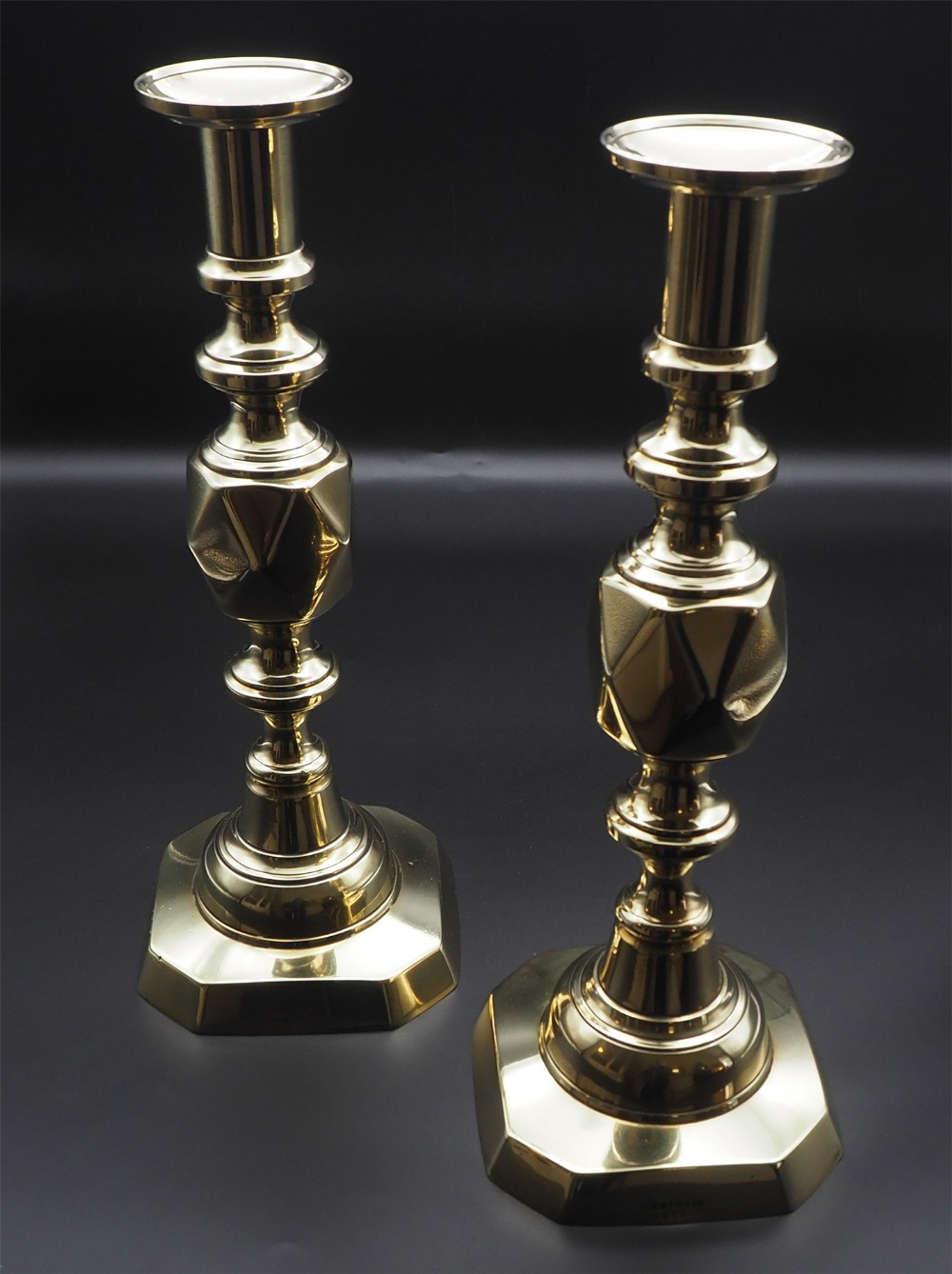 A pair of polished brass Victorian King of Diamonds candlesticks featuring faceted central knops and octagonal bases.
