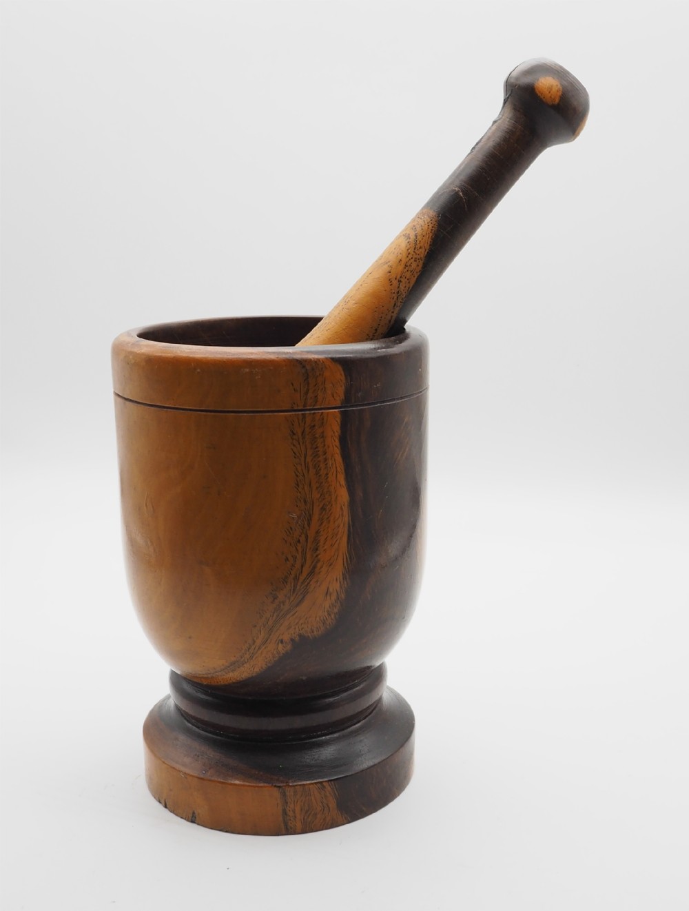 A 19th-century turned lignum vitae mortar and matching pestle featuring distinct dark brown and honey-coloured wood grain.