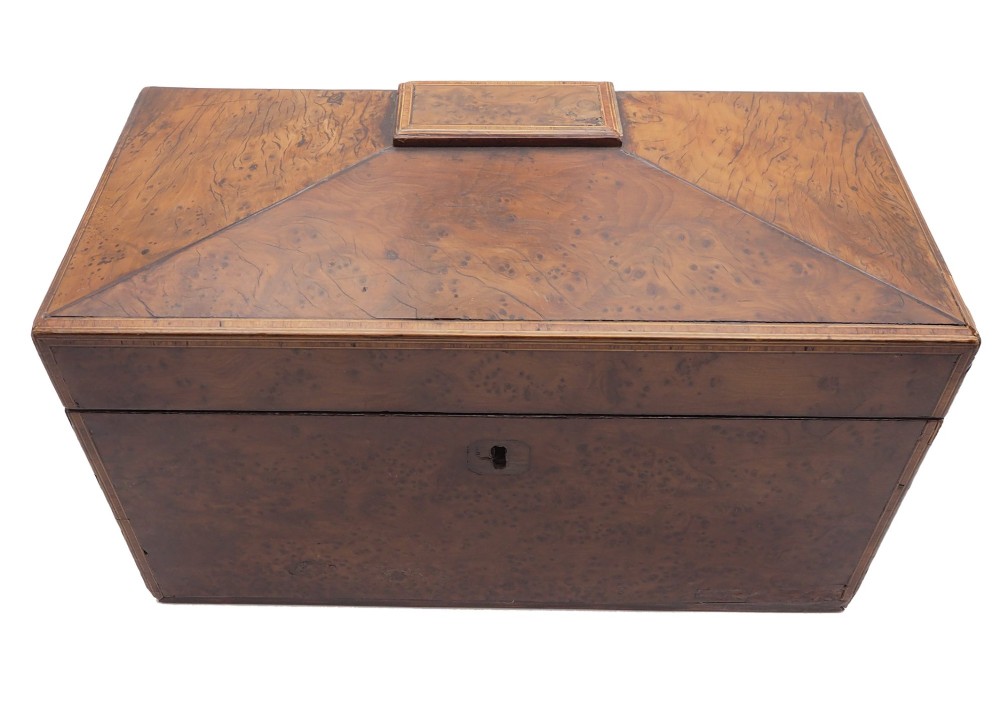 A Regency period sarcophagus-shaped tea caddy crafted from figured burr yew wood with fine string inlay.