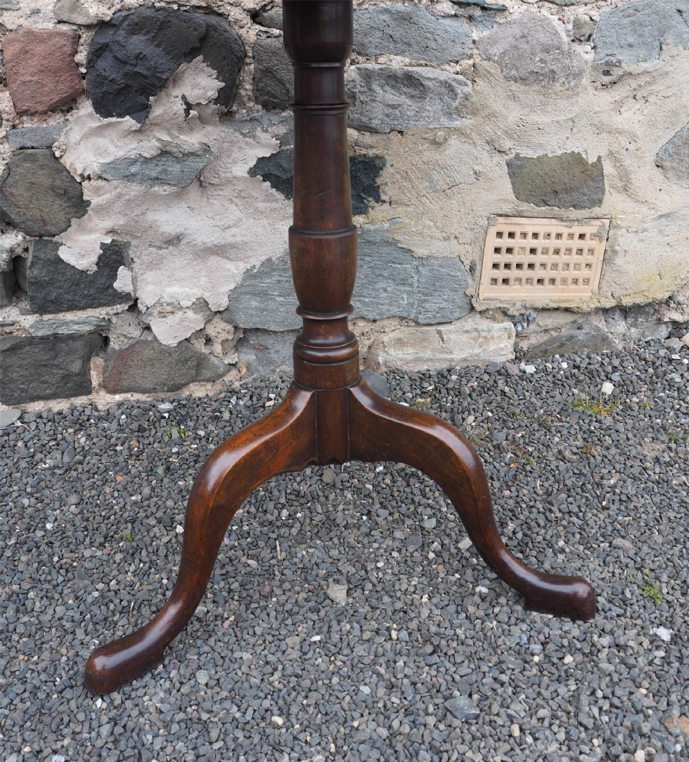 A Georgian mahogany tilt-top table shown upright with a circular top, turned central pedestal, and tripod cabriole legs. View IV