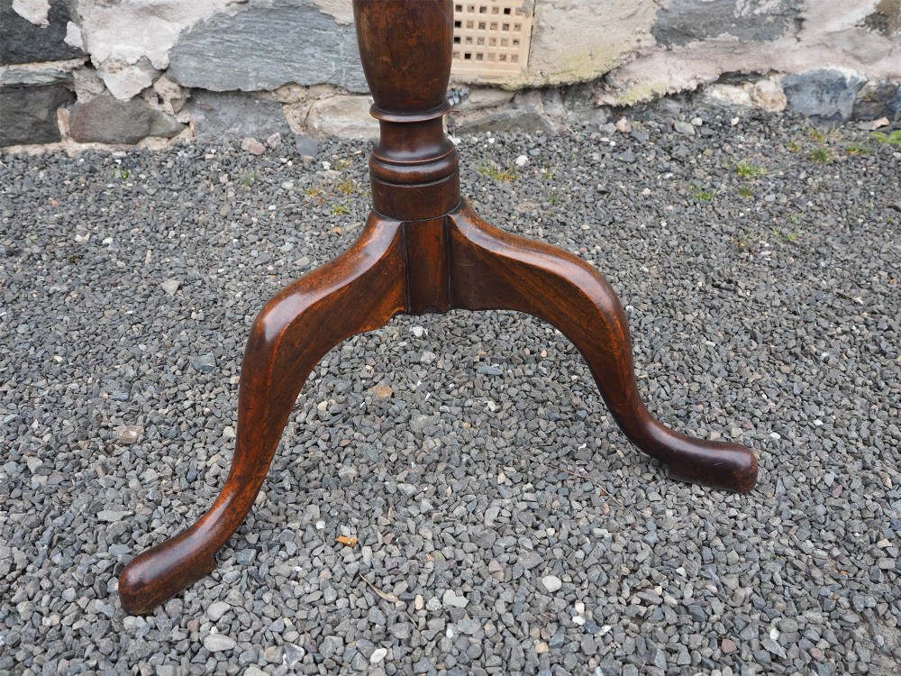A Georgian mahogany tilt-top table shown upright with a circular top, turned central pedestal, and tripod cabriole legs. View V
