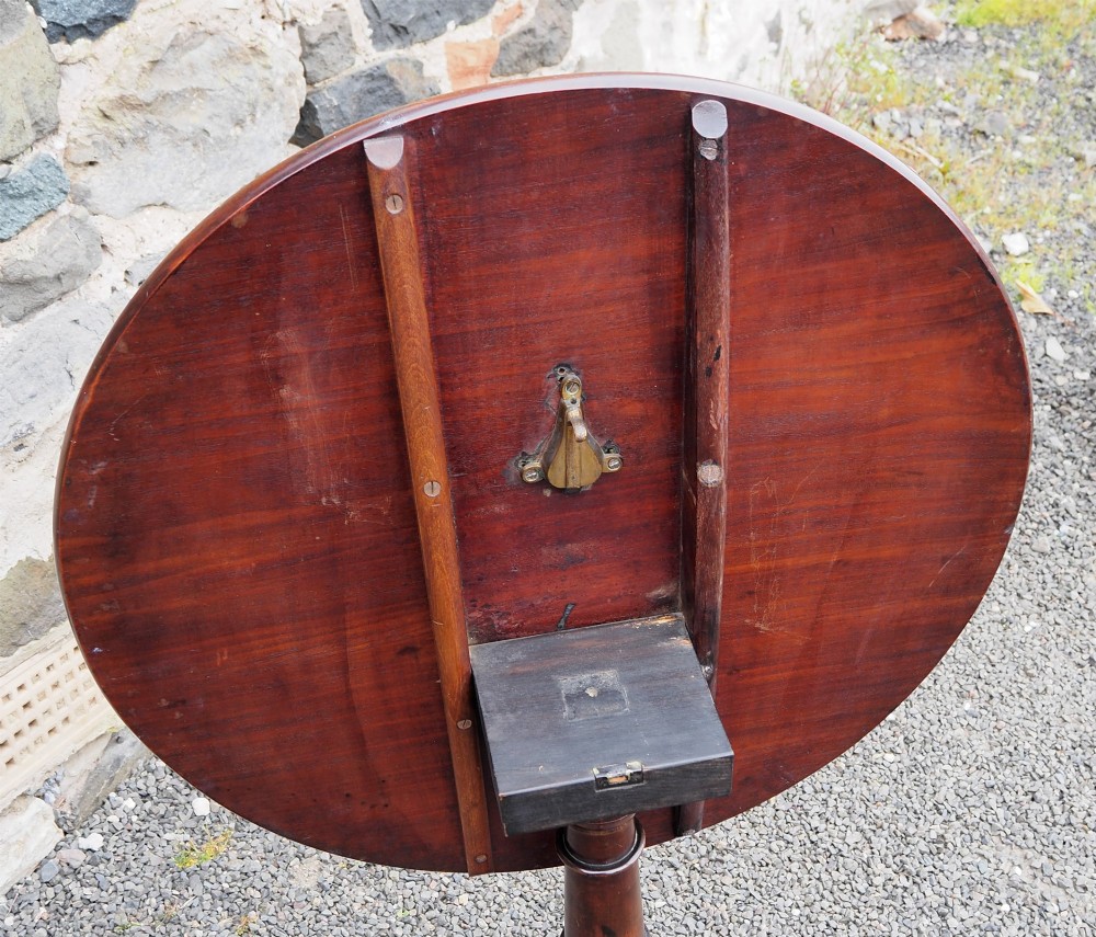 A Georgian mahogany tilt-top table shown upright with a circular top, turned central pedestal, and tripod cabriole legs. View VI