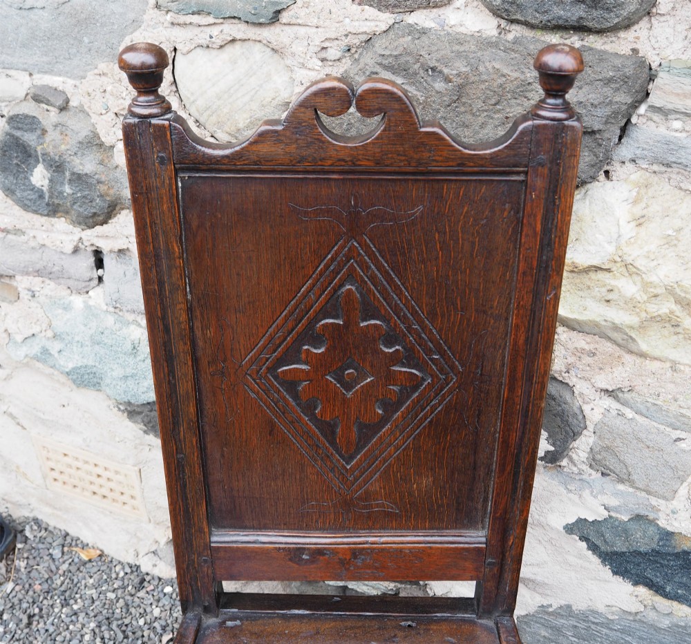 A pair of dark carved oak 17th-century hall chairs featuring geometric diamond back panels and turned legs. View IV
