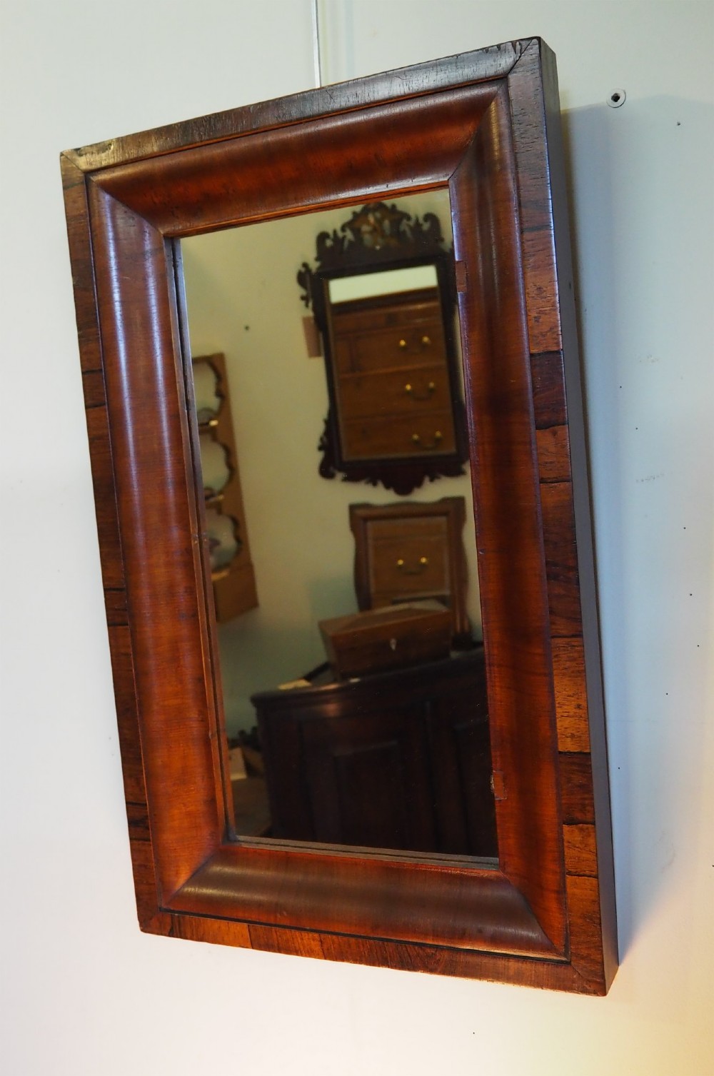 A 19th-century rectangular wall mirror featuring a deep cushion moulding frame crafted from dark rosewood veneer with mitred corners.
