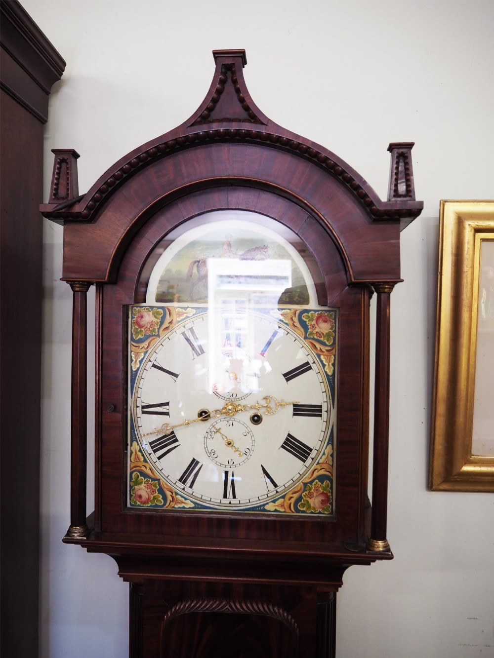 A tall Scottish mahogany longcase clock featuring a painted arch dial depicting an equestrian figure, flame mahogany cabinet trunk, and reeded side columns. View II