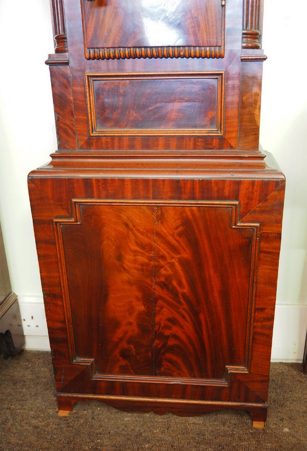 A tall Scottish mahogany longcase clock featuring a painted arch dial depicting an equestrian figure, flame mahogany cabinet trunk, and reeded side columns. View IV