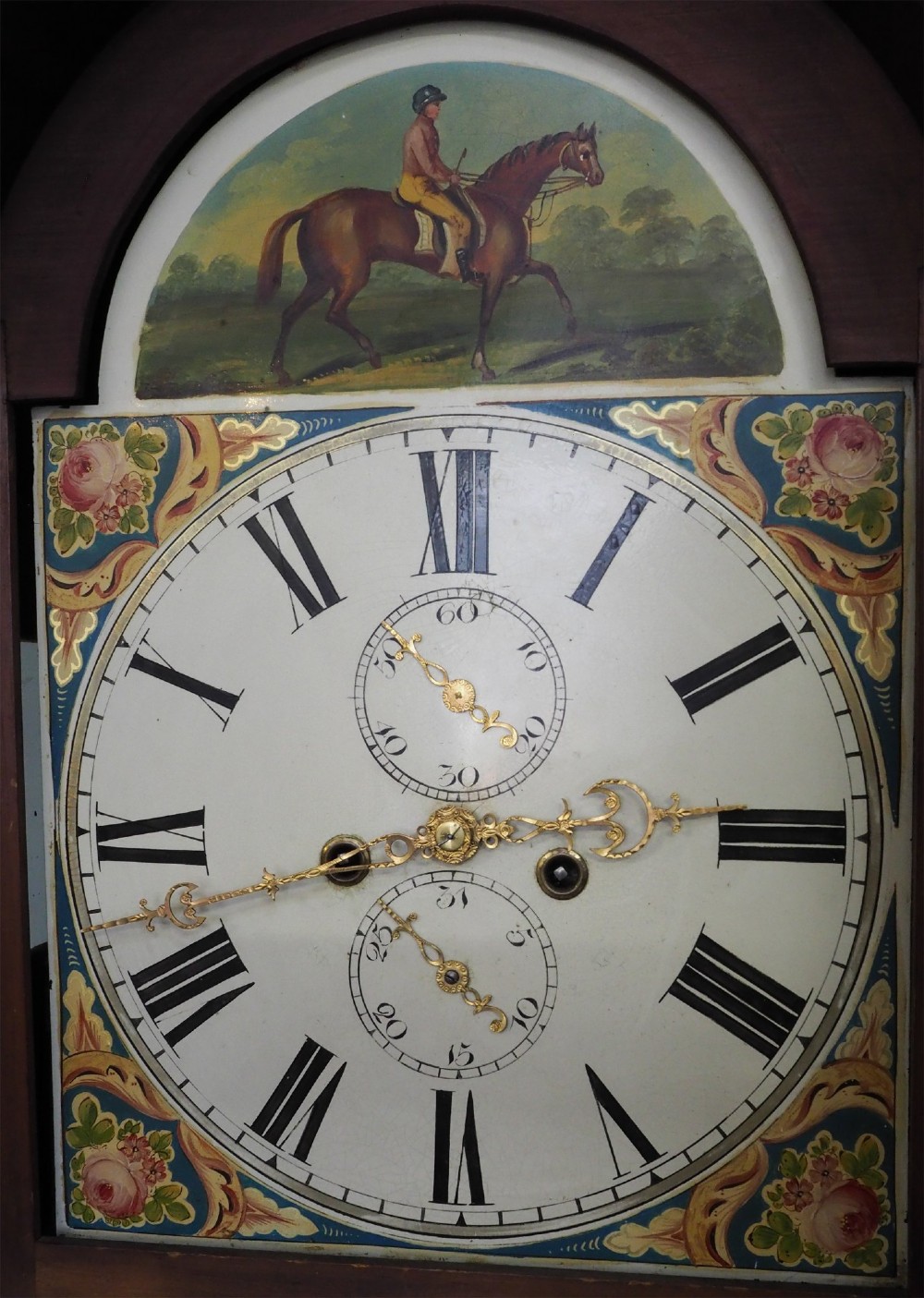 A tall Scottish mahogany longcase clock featuring a painted arch dial depicting an equestrian figure, flame mahogany cabinet trunk, and reeded side columns. View V
