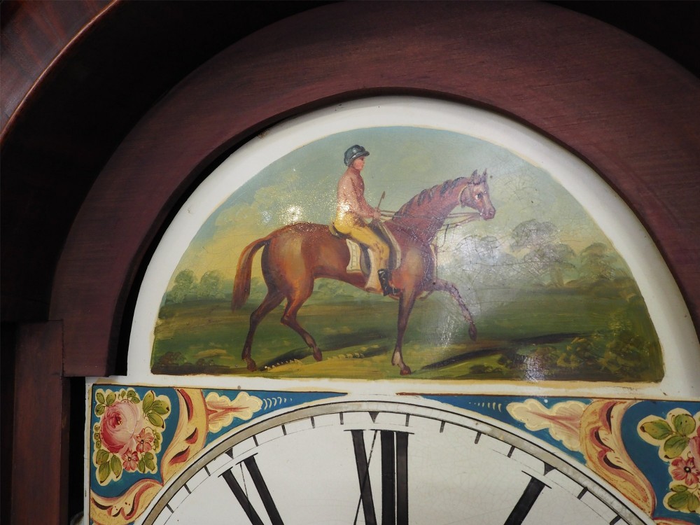 A tall Scottish mahogany longcase clock featuring a painted arch dial depicting an equestrian figure, flame mahogany cabinet trunk, and reeded side columns. View VI