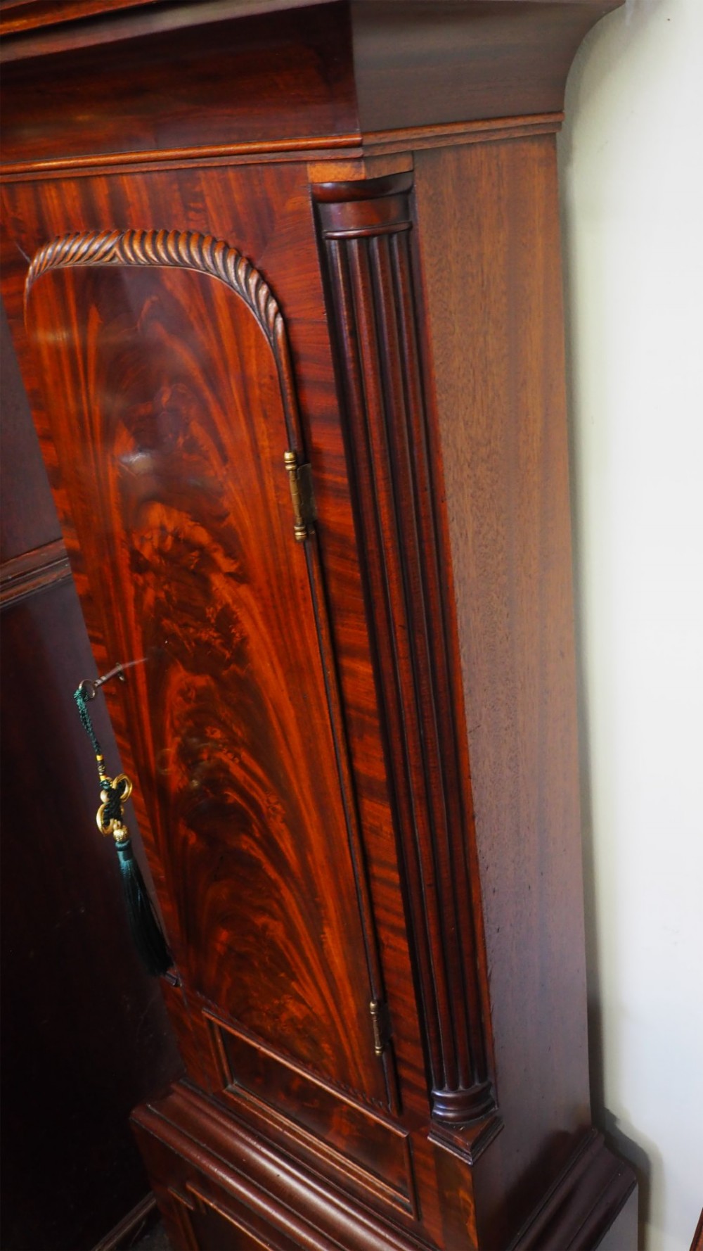 A tall Scottish mahogany longcase clock featuring a painted arch dial depicting an equestrian figure, flame mahogany cabinet trunk, and reeded side columns. View VIII