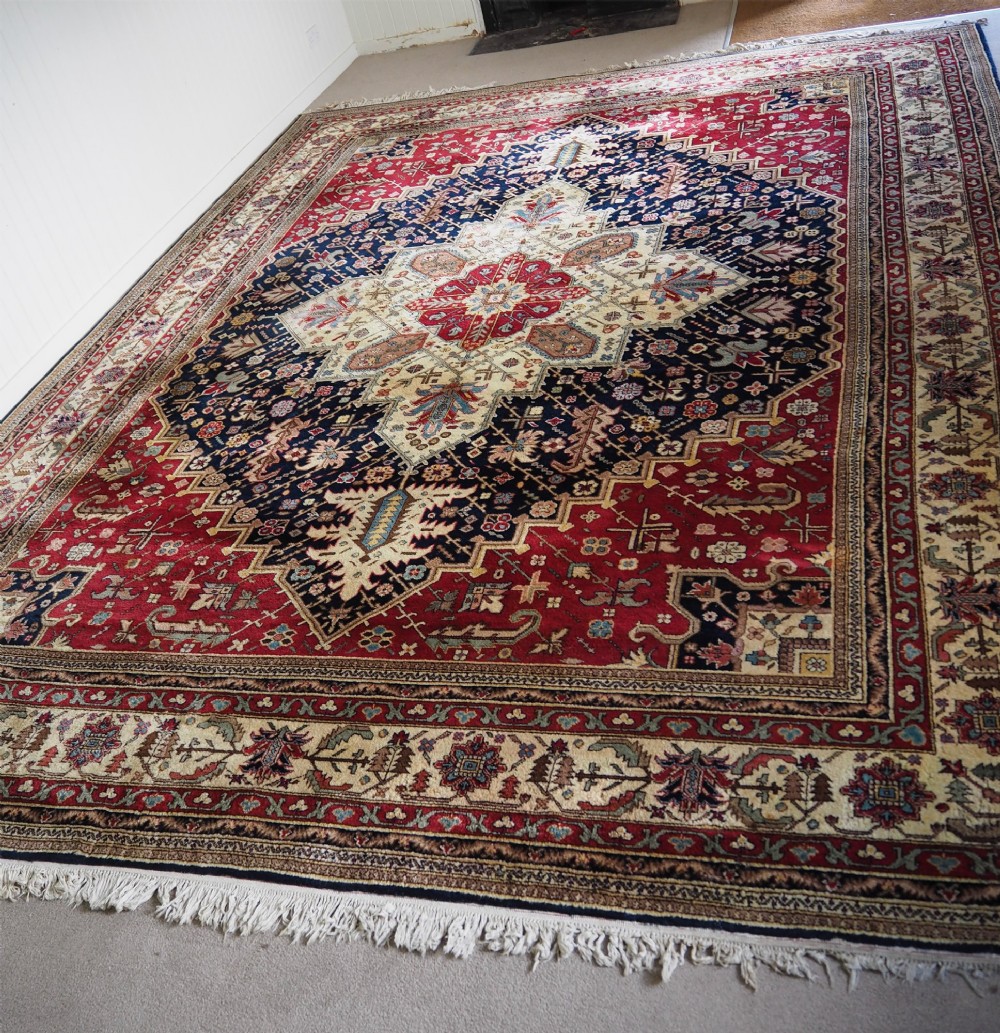 A large hand-knotted Persian wool carpet featuring a central cream medallion surrounded by navy blue and crimson sections filled with intricate floral motifs and framed by a detailed border. View II