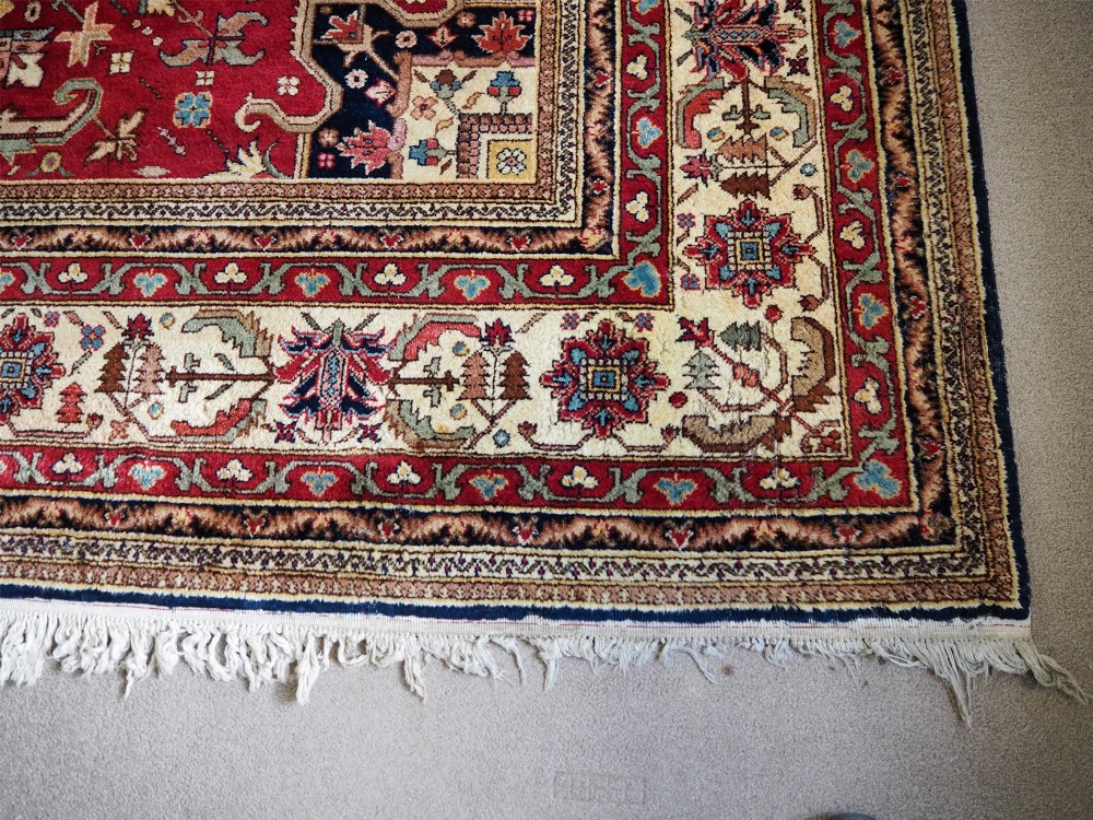 A large hand-knotted Persian wool carpet featuring a central cream medallion surrounded by navy blue and crimson sections filled with intricate floral motifs and framed by a detailed border. View III