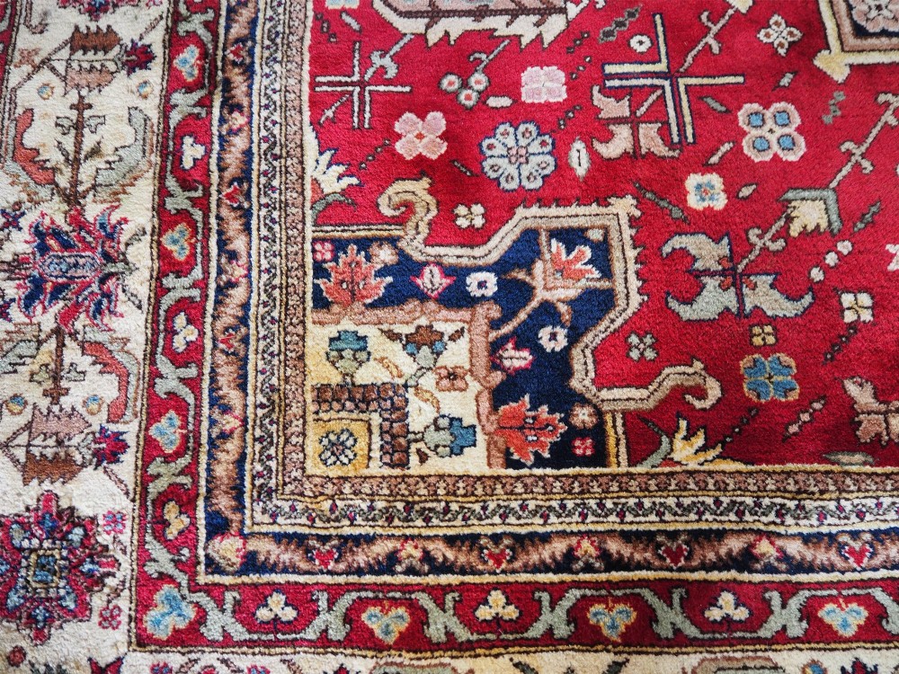 A large hand-knotted Persian wool carpet featuring a central cream medallion surrounded by navy blue and crimson sections filled with intricate floral motifs and framed by a detailed border. View VIII